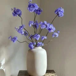 Beige vaas mat met blauw paars zijden bloesemtakken